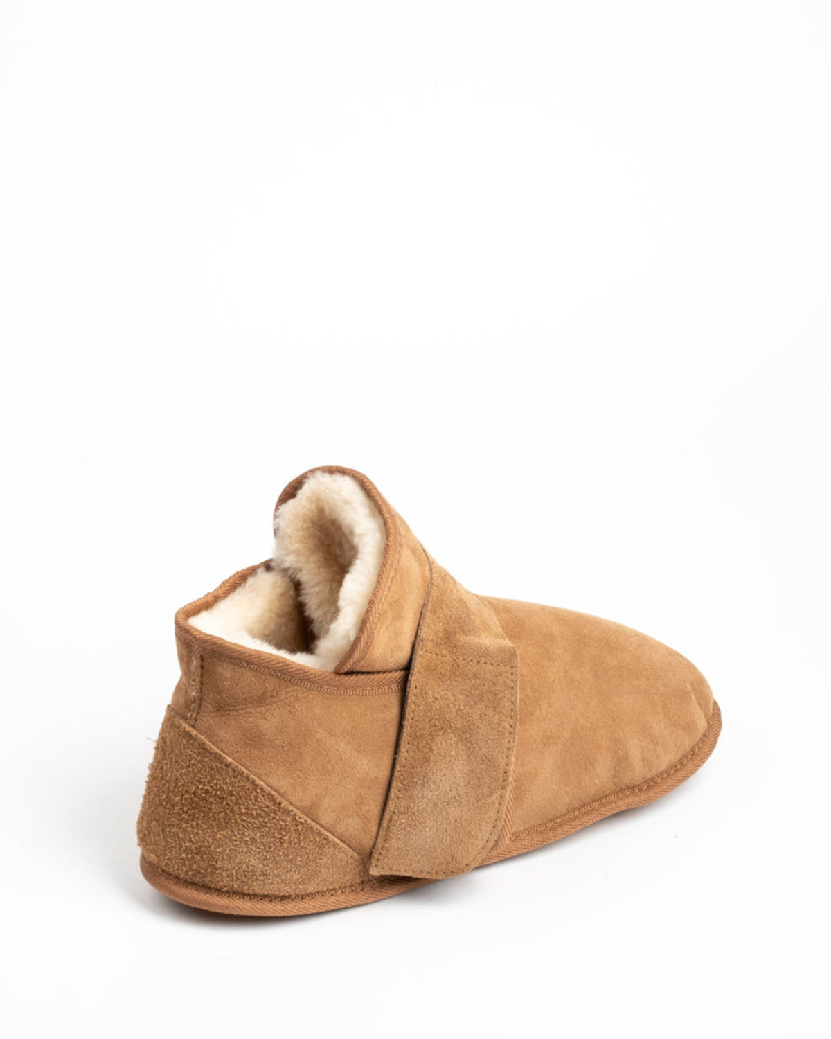 Tan slipper with shearling lining on a white background