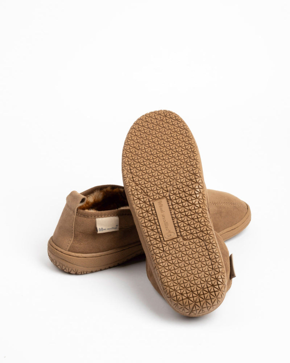 Pair of brown sheepskin slippers with textured sole on a white background